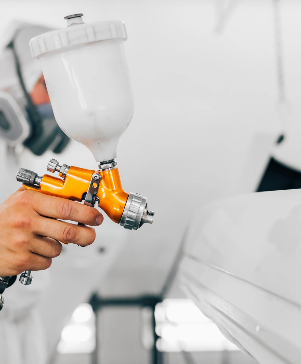 Person using a spray gun to apply paint in a controlled environment.