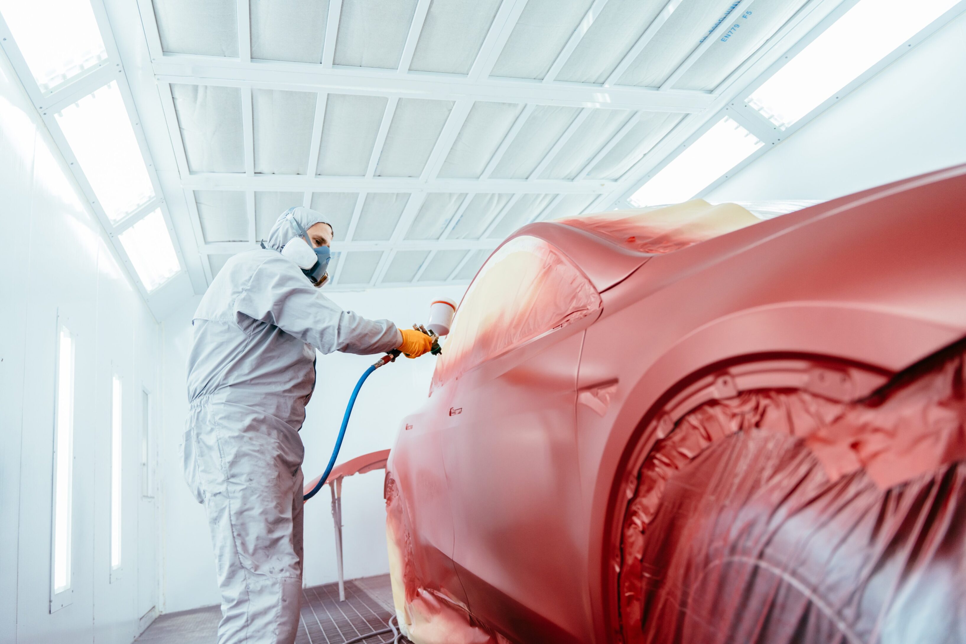 A person spraying paint on the back of a car.