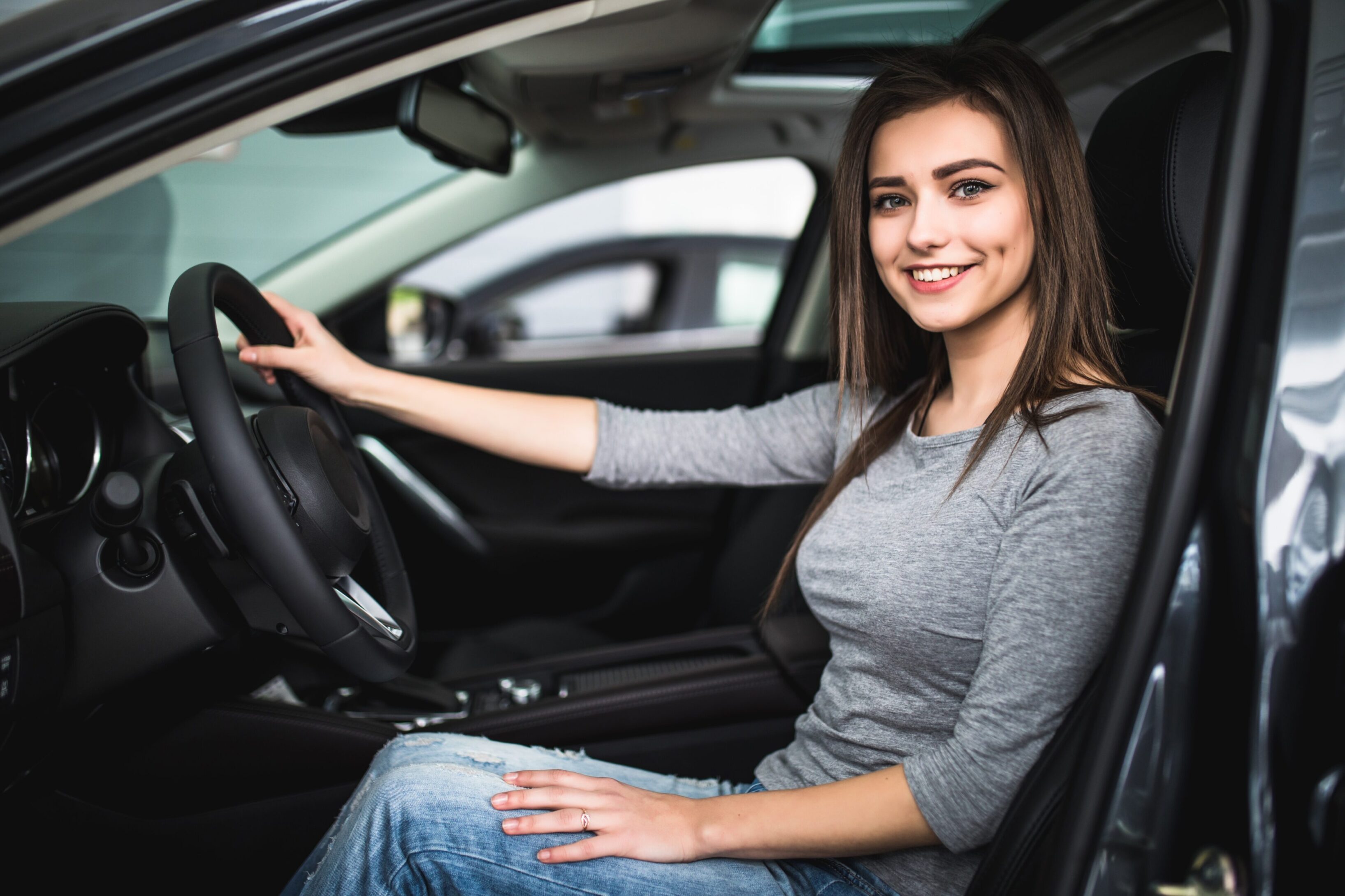 A woman sitting in the driver 's seat of her car.