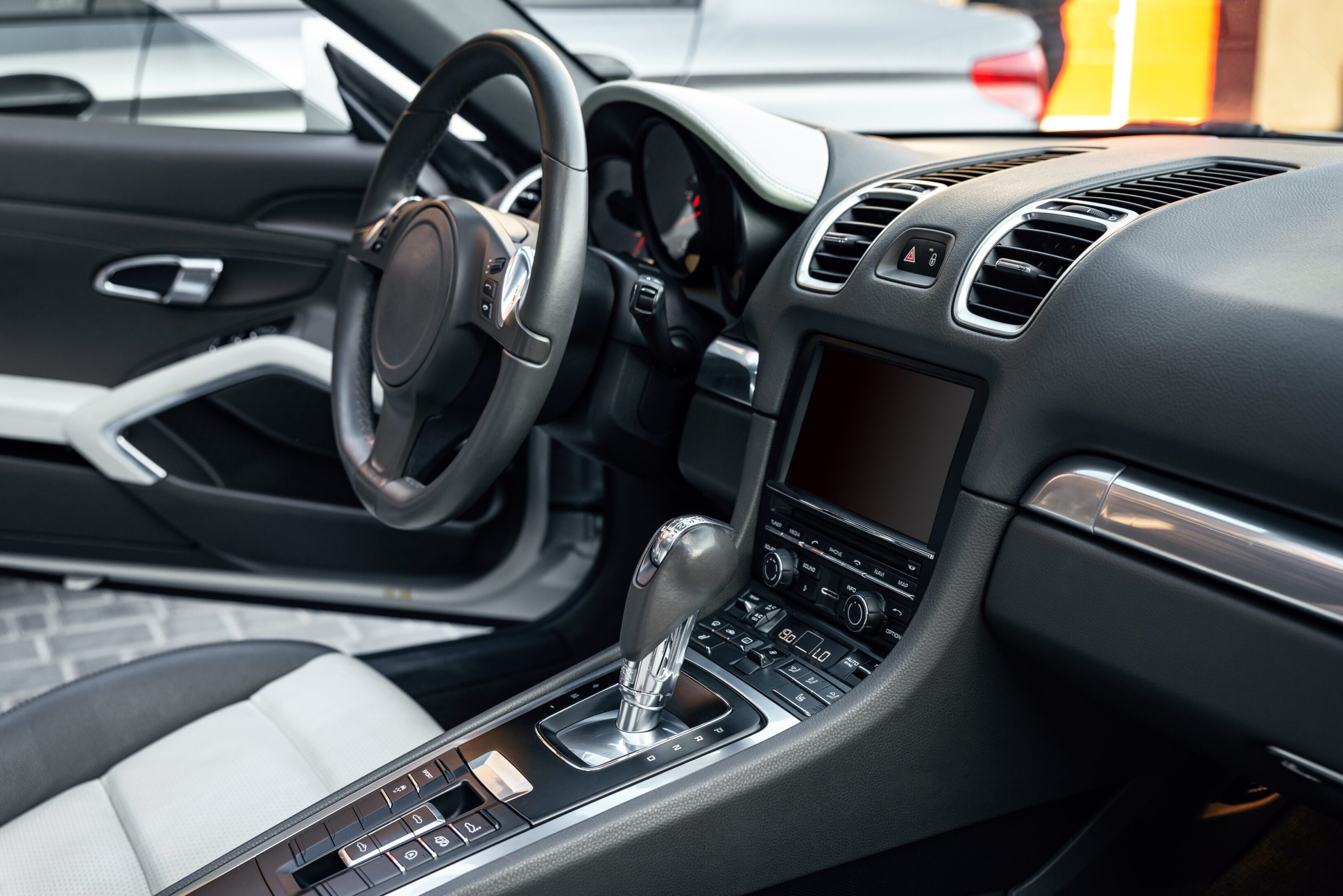 A car 's interior is shown with the steering wheel and dashboard.