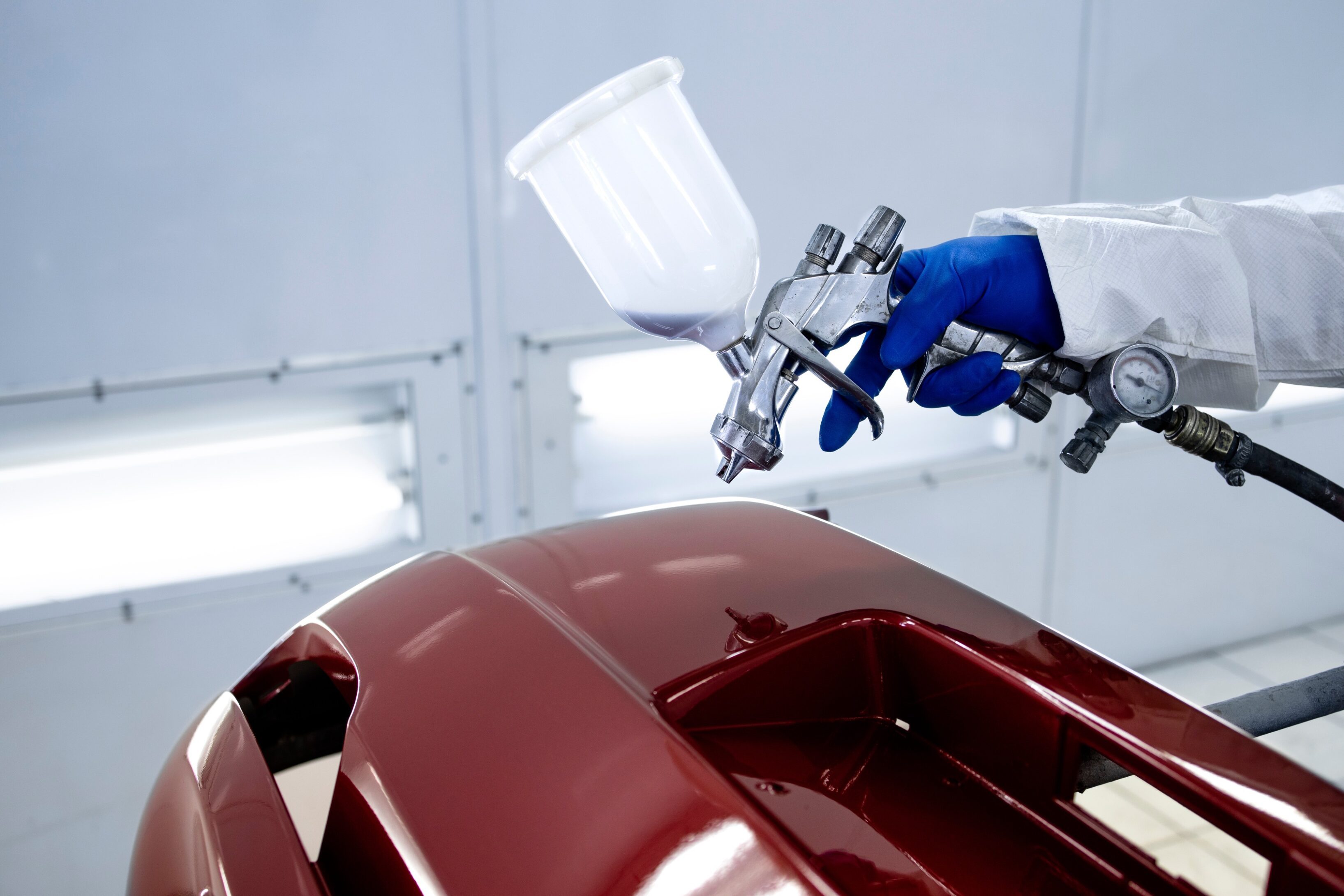 A person painting a car with red paint.